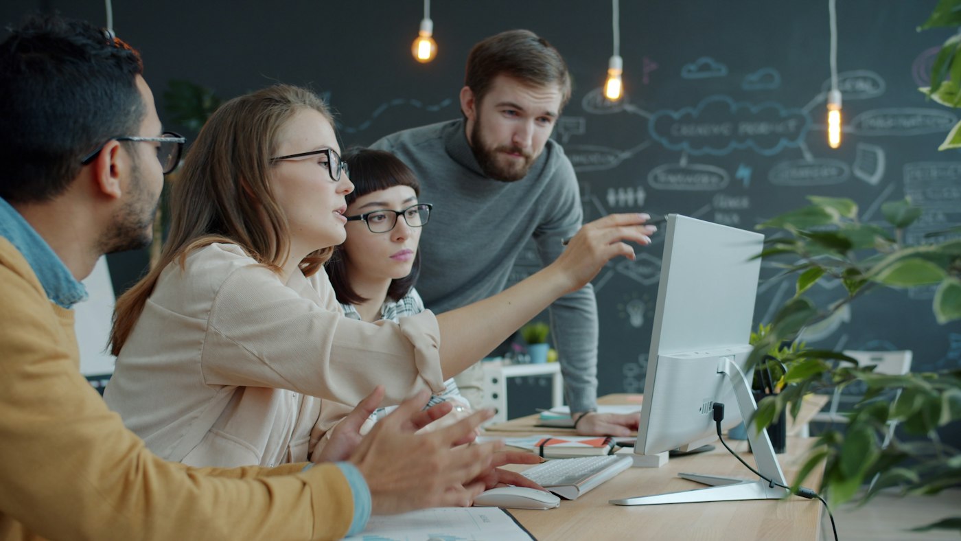 Colleagues discussing work at a computer
